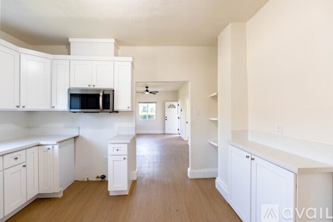 A kitchen with white cabinets and a microwave oven.