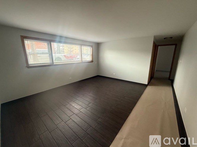 A room with a brown floor and a window.