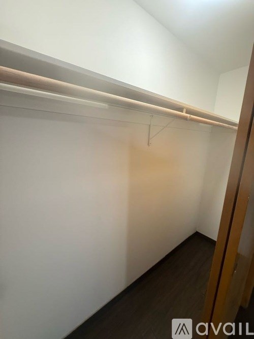 A white wall with a coat rack and a wooden door.