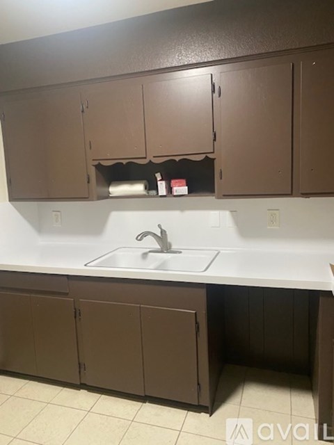 A kitchen with brown cabinets and a white sink.