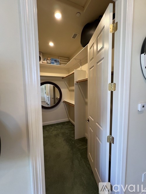 A hallway with a mirror on the wall and a door on the right.