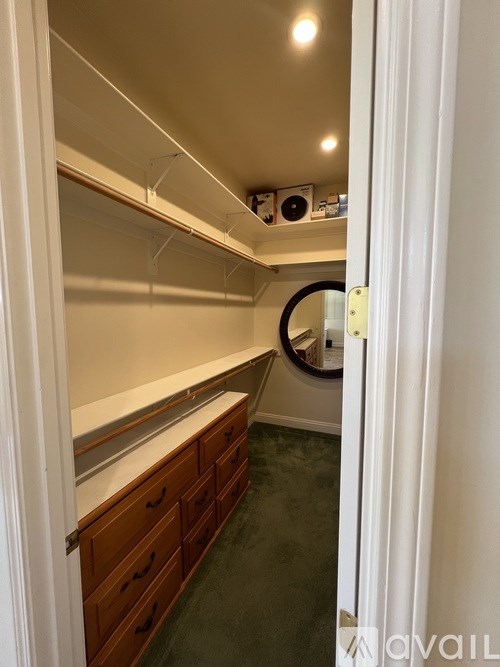 A walk-in closet with a mirror and wooden drawers.