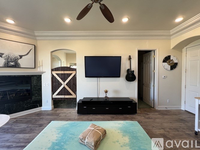 A living room with a flat screen TV mounted on the wall above a black entertainment center.