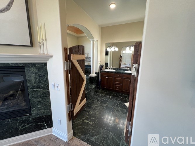 A bathroom with a marble floor and a wooden door.
