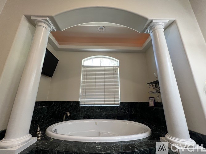A bathroom with a large tub and a window with blinds.
