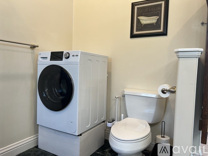 A white washing machine and toilet in a small bathroom.