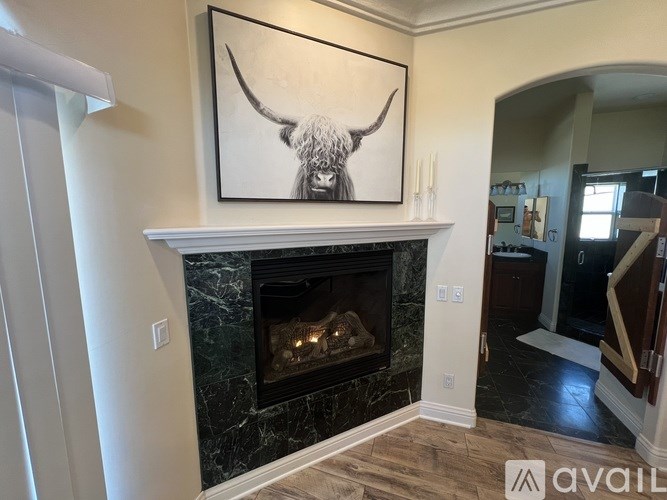 A black and white painting of a bull head is mounted above a fireplace.