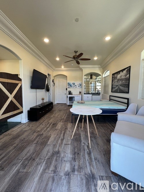 A spacious room with a ceiling fan and a bed in the background.