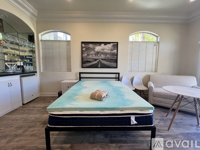 A bedroom with a bed, a couch, and a painting on the wall.