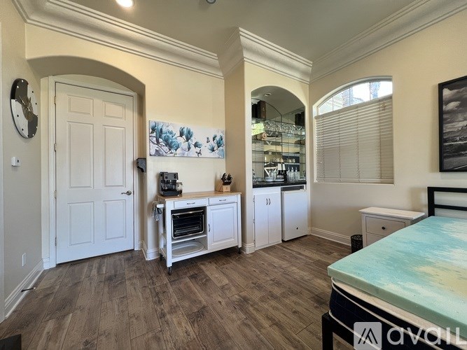 A bedroom with a bed, a vanity, and a kitchenette.