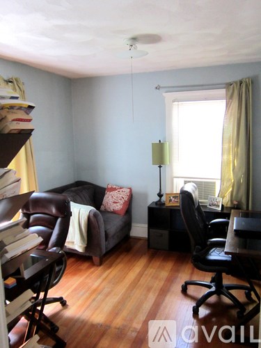 A living room with a brown leather couch and a black chair.