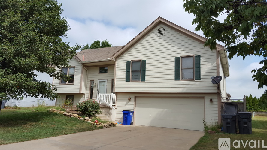 A house with a blue trash can in front of it.