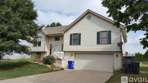 A house with a blue trash can in front of it.