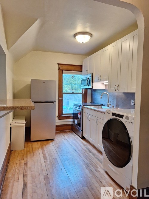 A small, clean, and well-organized kitchen with wooden floors and white cabinets.