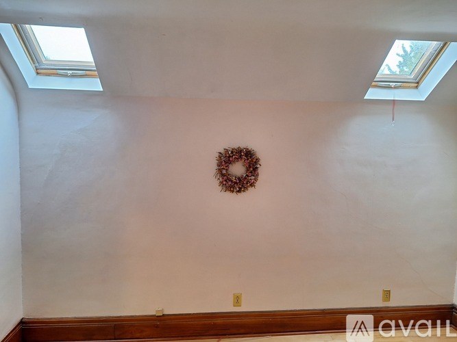 A room with a wreath on the wall and skylights.