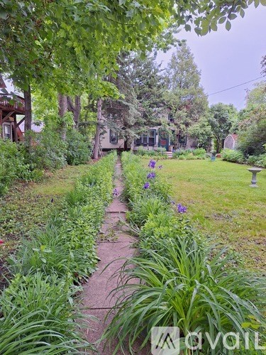 A garden pathway surrounded by greenery and a bench.