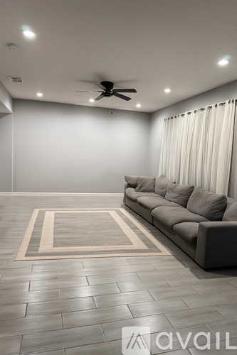 A living room with a grey sofa and a rug.