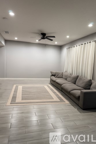 A living room with a grey sofa and a rug.