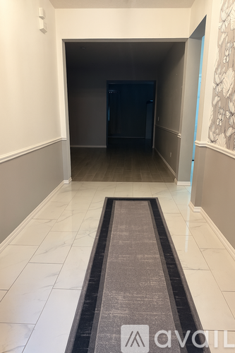 A hallway with a carpeted entrance mat leading to a dark room.