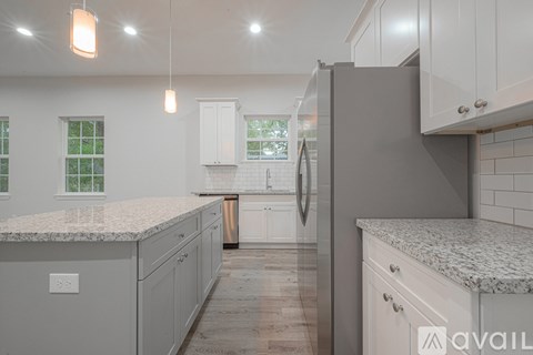 A kitchen with white cabinets and a marble countertop.