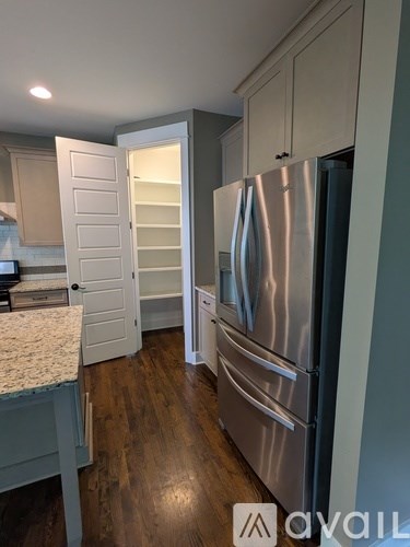 A kitchen with a stainless steel refrigerator and wooden floors.
