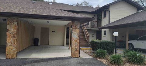 A house with a stone pillar and a car parked in front.