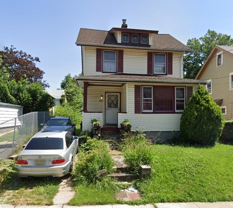 A two-story house with a car parked in front.