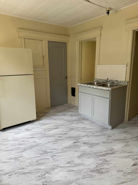 A kitchen with a marble floor and a white fridge.