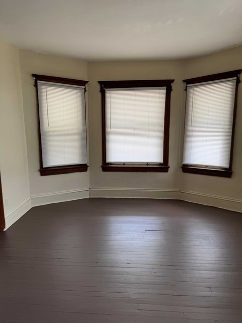 A room with wooden floors and three windows.