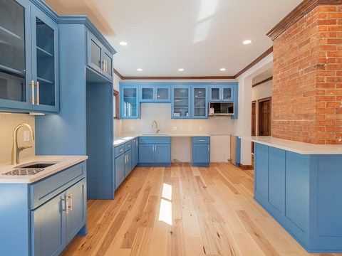 A kitchen with blue cabinets and wooden floors.