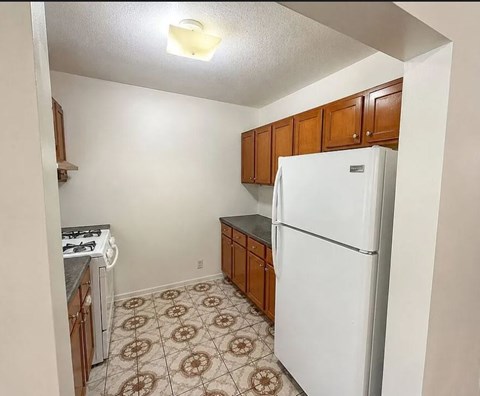 A kitchen with a white refrigerator and brown cabinets.