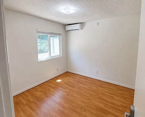 A room with a window and wooden flooring.