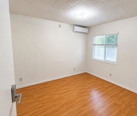 A room with a window and a wooden floor.