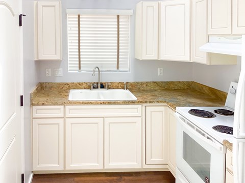 A kitchen with white cabinets and a granite countertop.