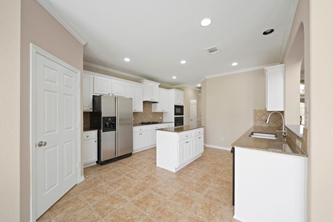 A kitchen with white cabinets and a tiled floor.