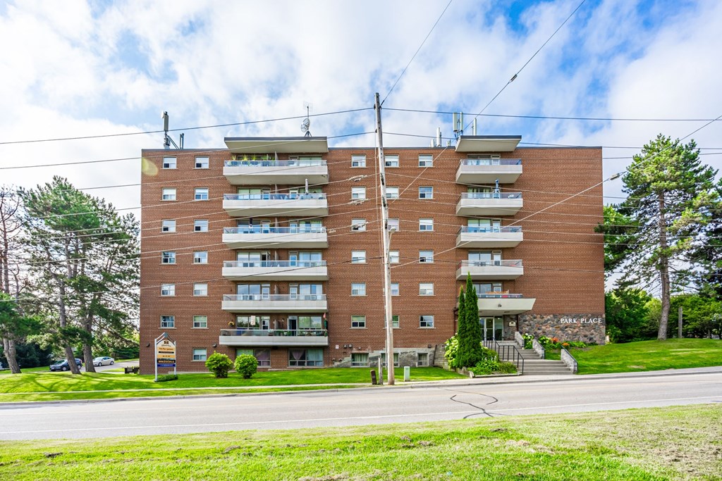 A large brick apartment building with a green lawn in front.