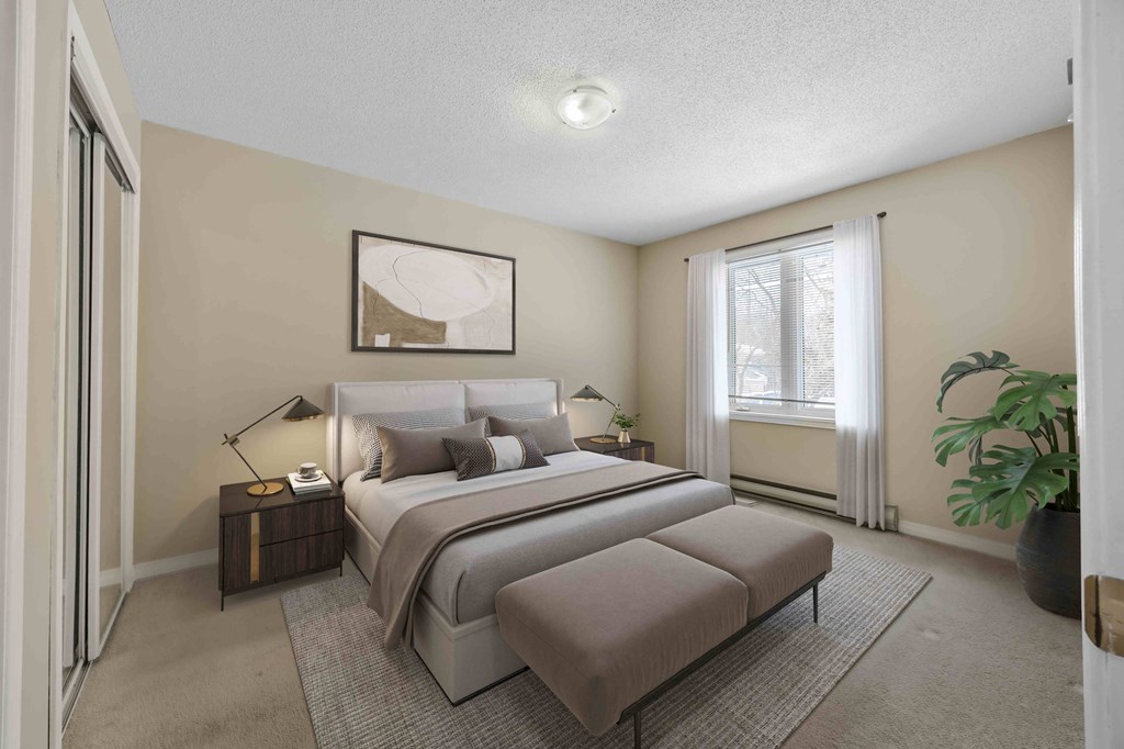 A bedroom with a large bed and a potted plant.