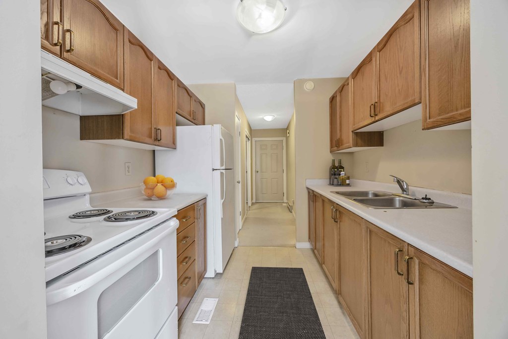 A kitchen with white appliances and wooden cabinets.