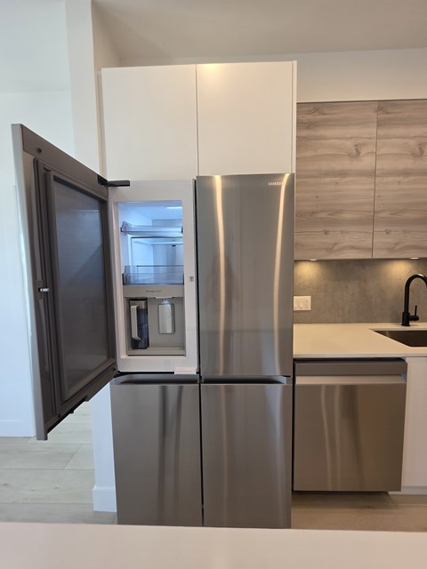 A stainless steel refrigerator with its door open in a kitchen.