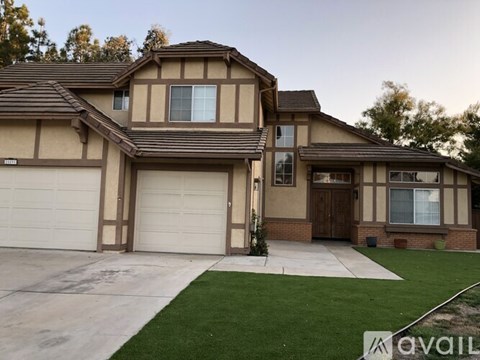 A house with a brown and beige exterior and a white garage door.
