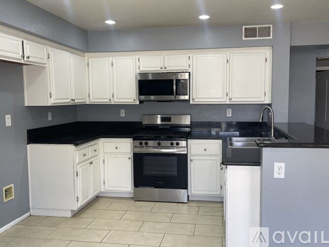 A kitchen with a black counter top and a white sink.