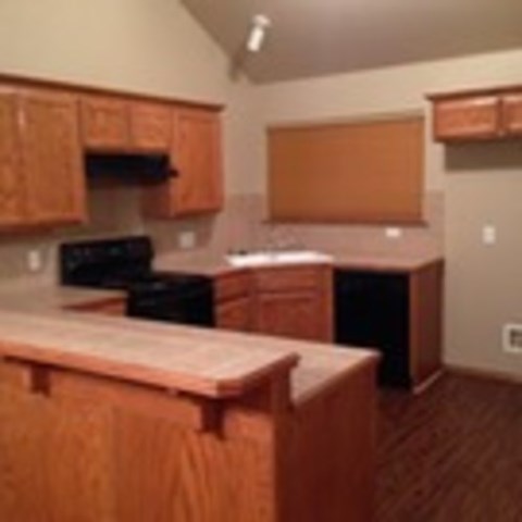 A kitchen with wooden cabinets and a black stove top oven.