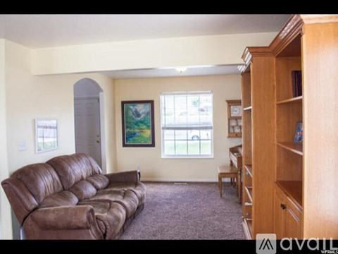 A living room with a brown leather couch and a wooden bookcase.