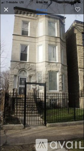 A tall, cream-colored building with a black gate in front.