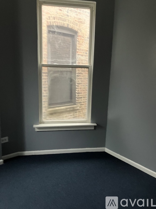 A room with a large window and a view of a brick building outside.