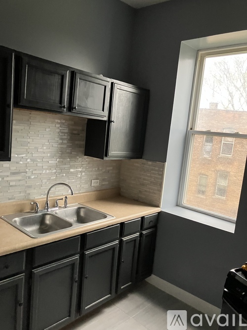 A kitchen with black cabinets and a brick backsplash.