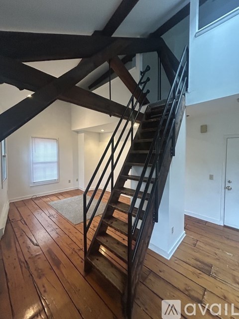 A wooden staircase with a metal railing leads up to a second floor.