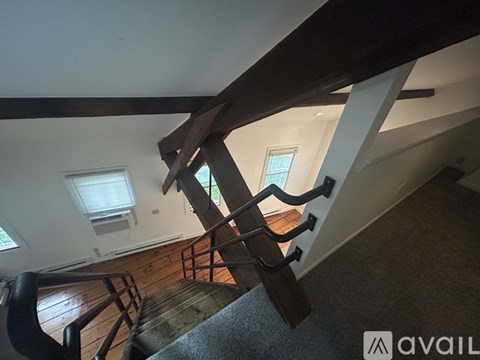 A staircase with a wooden handrail and a carpeted runner.