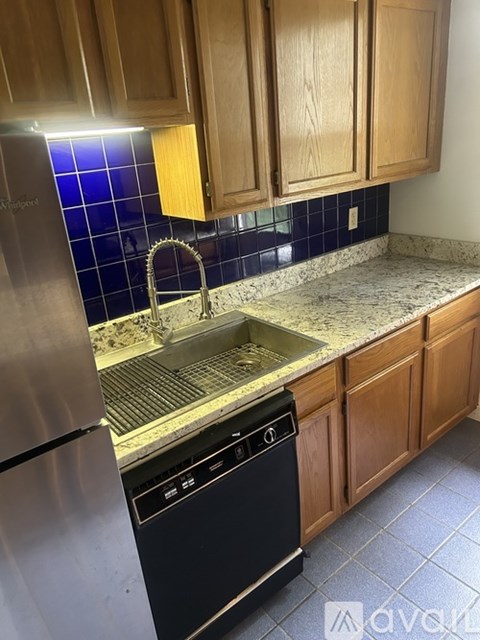 A kitchen with a black dishwasher and a stainless steel refrigerator.