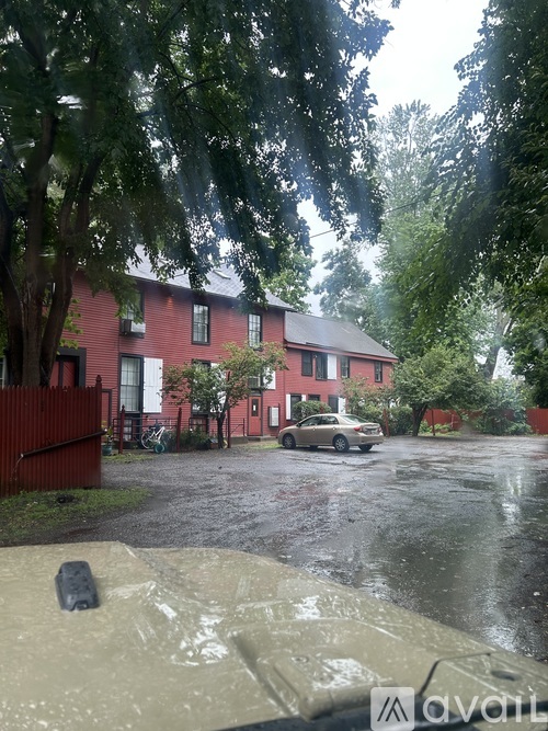 A car is parked in front of a red house.